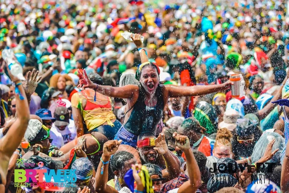 Jouvert crowd celebrating beneath a spray of water